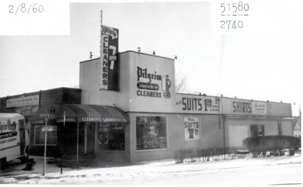 Historic Pilgrim Cleaners storefront with its tall vertical sign and delivery truck at the left
