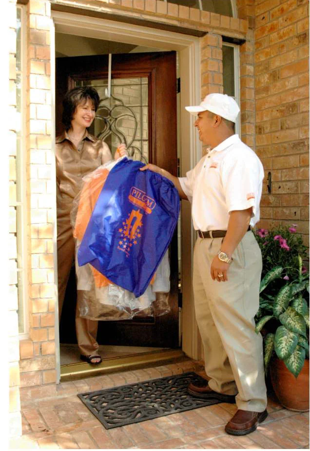 A Pilgrim Cleaners driver delivering garments to a customer at home