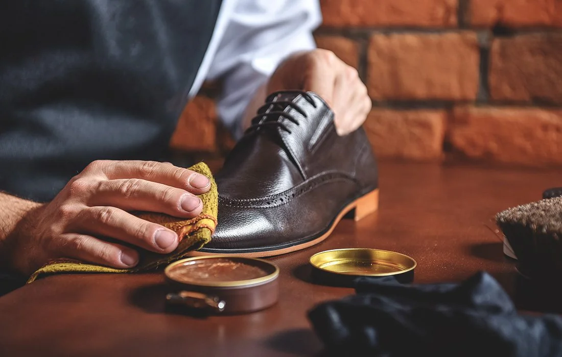 A craftsperson polishing a leather dress shoe by hand